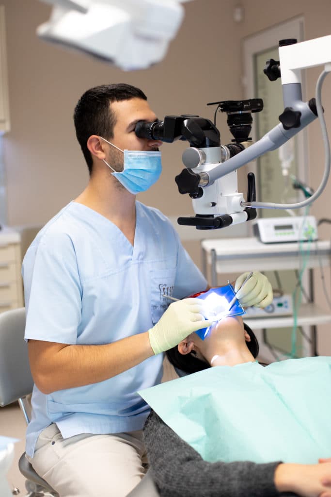 Medic stomatolog efectuând un tratament de canal sub microscop